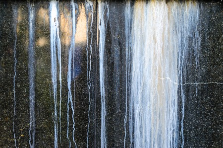 Black Polished Granite Wall with White Outgrowths Leaking from the Weather. Streaks on the Wallの写真素材