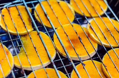 Baked pumpkin slices on the grill grid. The process of cooking vegetables on the grill in the open airの写真素材