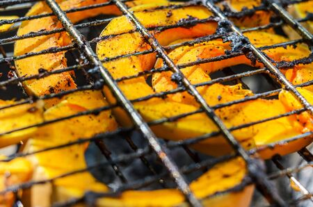 Baked pumpkin slices on the grill grid. The process of cooking vegetables on the grill in the open airの写真素材
