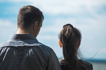 Couple stands on the shore of the lake. Backs of man and woman