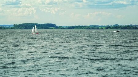 Movement in the gavon. Small sailing and motorboats go on the surface of water in the distance. Landscape of the bay on a sunny dayの写真素材