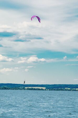 A kiteboarder is pulled across water by a power kite. Kitesurfer high in flightの写真素材