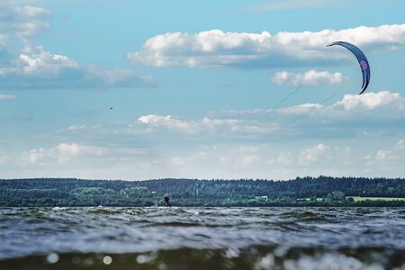 A kiteboarder is pulled across water by a power kite