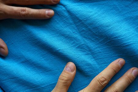 Hands on blue linen fabric view from above. Texture of natural fabricの写真素材