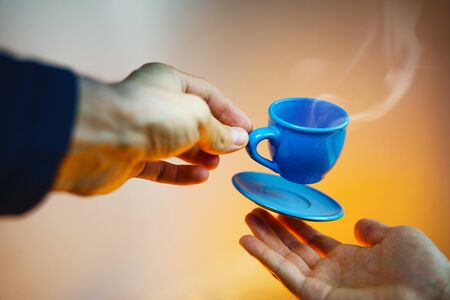 Floating blue cup of espresso with hands. First-person view. Mock up of soaring in the air cup of hot coffee. Levitate conceptの写真素材