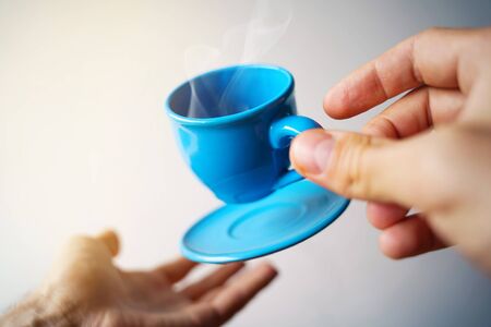 Floating blue cup of espresso with hands. First-person view. Mock up of soaring in the air cup of...