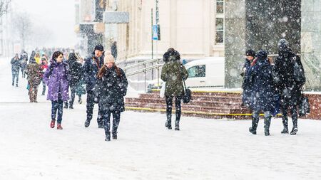 Winter city sidewalk. People walking along an icy snowy pavement. City dwellers in the winter. Abstract winter weather backgroundの写真素材