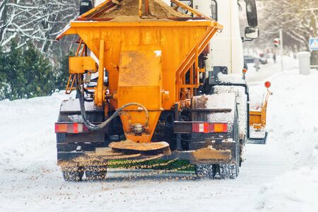 Municipal car sprinkles snowy roads with sand and salt. Snow blower. Winter anti-slip road handling...