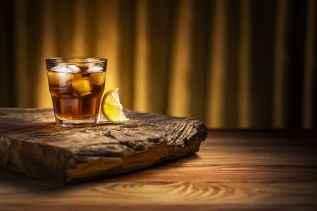 A glass of alcoholic beverage with a slice of lemon on a wooden table.の写真素材