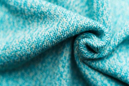 Crumpled texture of a blue turquoise knitted fabric. Sweater background