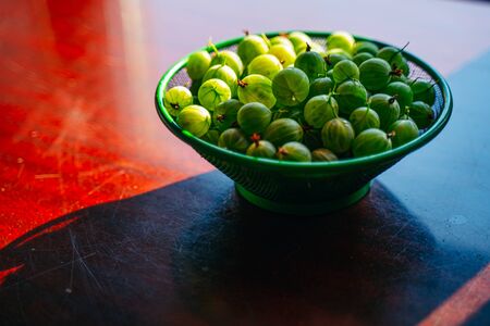 Heap of green washed gooseberry fruit in a colander on table top viewの写真素材