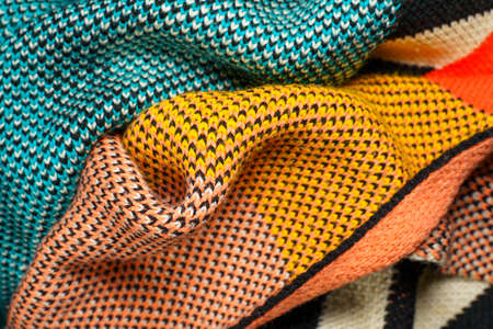 A pile of multi-colored knitted fabrics