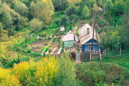 Country cottage among autumnal trees. Buildings surrounded by forestの写真素材