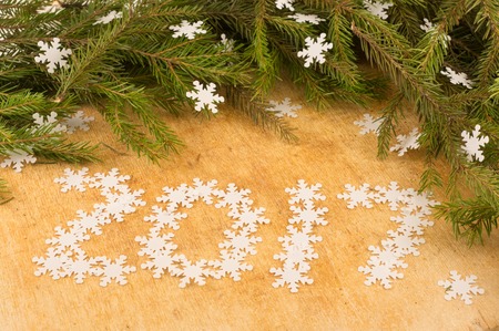 The branches of Christmas trees on the background of wooden boards and snowflakes  inscription. ...