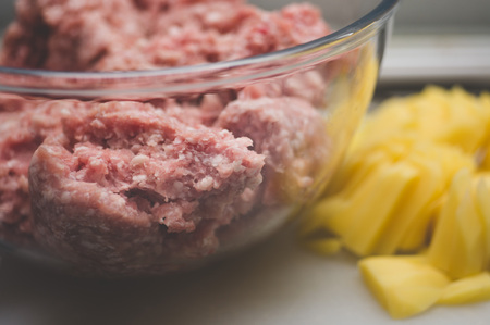Sliced potato for soup and meat stuffing for making meatballs. Soup with meatballs and pasta prepear in process.の写真素材