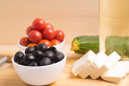 Greek salad with vegetables, feta cheese, black olives in process. Wooden background . Top viewの写真素材