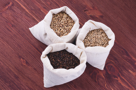 Pale, caramel, chocolate malt in a bags. Craft beer brewing from grain barley malt in process. Ale or lager from pale or dark pilsner malt. wooden backgroundの写真素材