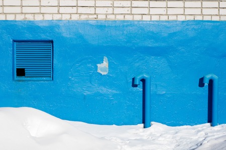 typical view of the socle of a multi-storey building in Russia. A wall with pipes from the basement and a grating ventilation.の写真素材