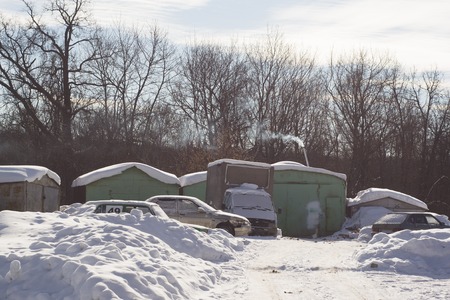 Winter landscape with garages and snow-covered cars. Frosty day at the edge of the city.の写真素材