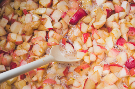 cook apple jam and stir with a white plastic spoon. process of making apple jam marmalade at homeの写真素材