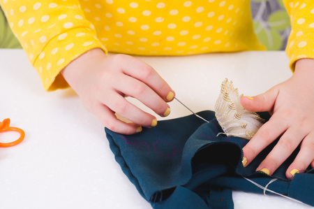 baby hands with a needle, busy sewing a flower to a green clothchildren's creativity and learning needlework.の写真素材