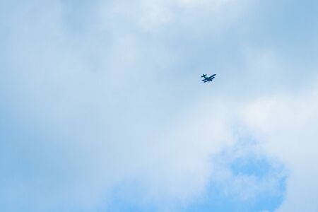 green airplane flying high in a cloudy blue sky. long-range shooting