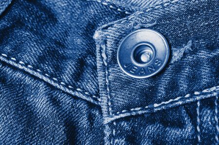 Jeans close-up. Clasps, seams, zippers,  button. Interlacing the fabric with a close-up.  toned  in classic blue trendy color of the year 2020の写真素材