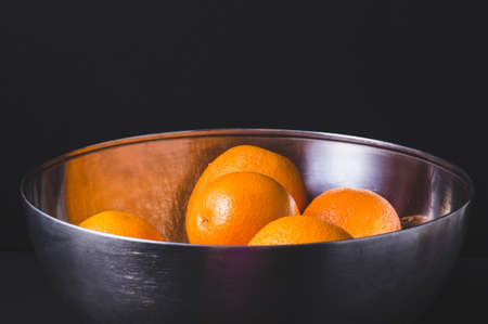 Oranges in a steel bowl with black background. delicious tasty juicy fruitの写真素材