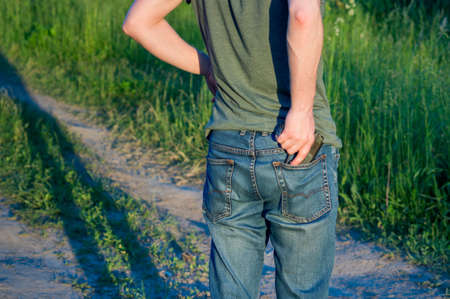 hidden weapon gun in jeans pocket. man with weapon, rear viewの写真素材