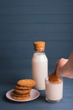 a pile of delicious homemade cookies on a white plate, a bottle of milk and a glass of milk on a blue wooden backgroundの写真素材