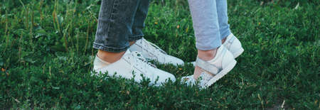 mother and daughter legs and shoes on the grass, only feet