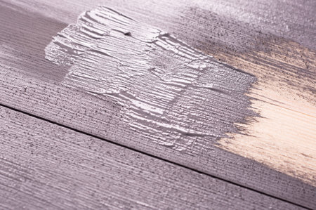 painting a wooden surface with a brush and gray paint. natural wooden texture. Renovation or repair construction.の写真素材
