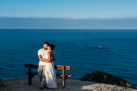 A couple in love meets the sunrise at the sea. Honeymoon. Honeymoon trip. Boy and girl at the sea. Man and woman traveling. Couple hugs. Couple kissing. Newly married couple. Lovers. Holiday romanceの写真素材