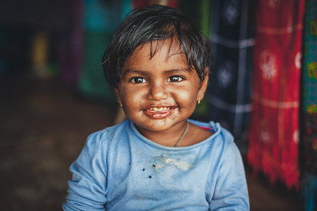 A little Indian girl looks at the camera. Chocolate baby. Indian child in old clothes. Portrait of a laughing childのeditorial素材
