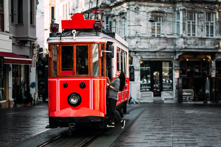 Girl in a vintage tram on the Taksim Istiklal street in Istanbul. Girl on public transport. Old Turkish tram on Istiklal street, Turkey. Portrait of a smiling young woman posing on a city streetの写真素材