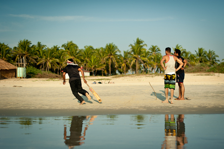 Friends play cricket on the beach of GOA in India. The guys play Indian baseball on the beach. Indian national sport. The game of cricket at sunsetのeditorial素材