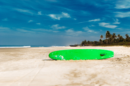 Surfboard on a tropical beach overlooking the ocean, blue sky background. Colored Board for surfing on the sand.の写真素材