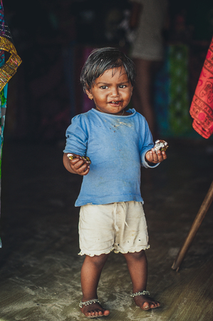 Poverty, photo of a little poor Indian girl in old ragged clothes, standing full-length. Chocolate babyのeditorial素材