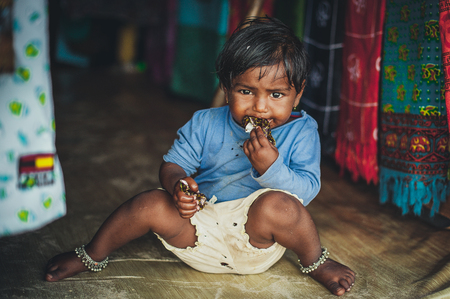 Poverty, a picture of a little poor Indian girl in old ragged clothes sitting on the floor. Chocolate babyのeditorial素材