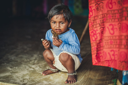 Poverty, a picture of a little poor Indian girl in old ragged clothes sitting on the floor. Chocolate babyのeditorial素材