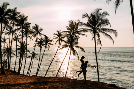 A couple in love meets a sunset on the sea among the palm trees.の写真素材