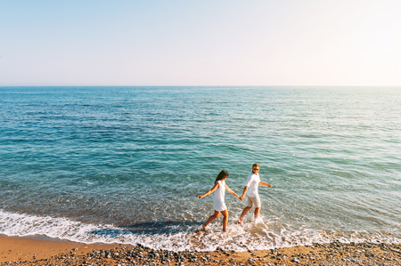 Couple in love having fun on the beach. Honeymoon trip. The couple are traveling. Man and woman on the beach. Happy couple. Run along the shore. Sea tour. Man and woman at sea. Wedding travel. Loversの写真素材