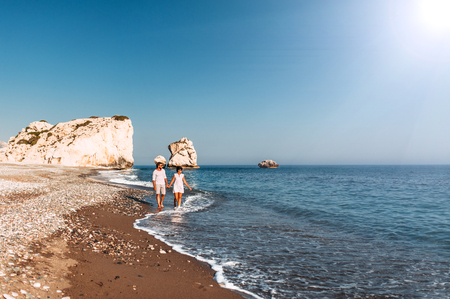 Happy couple holding hands walking on the sandy beach. Couple in love at sunset by the sea. Couple in love on vacation. Travel vacation concept. Romantic couple enjoying a beach walk at sunsetの写真素材