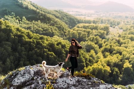 Woman with dog walking in the mountains. Canine friend. Walking with your pet. Travelling with a dog. A pet. Smart dog. Best friend. Mongrel. Sunset in the mountainsの写真素材