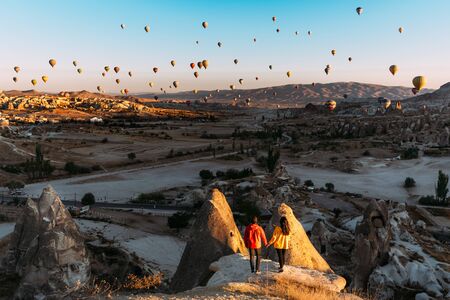 Man and woman greet the dawn among balloons. Couple in love among balloons.  Travelers in the mountains of Cappadocia, Turkey. Man and woman traveling. Flying on balloons. Festival of balloonsの写真素材