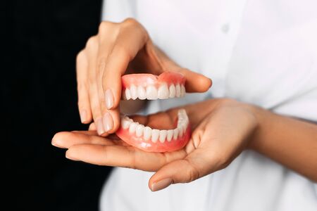 The dentist is holding dentures in his hands. Dental prosthesis in the hands of the doctor close-up....