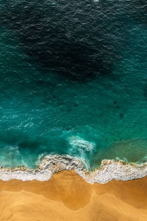 Beautiful sandy beach with turquoise sea, vertical view. Drone view of tropical turquoise ocean beach Nusa penida Bali Indonesia. Lonely sandy beach with beautiful waves. Beaches of Indonesia.の写真素材