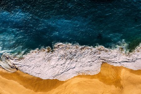 Beautiful sandy beach at sunset. Beach with yellow sand and sea foam. The sea wave covers the sandy beach with yellow sand at sunset. Aerial photography of the beach. beautiful Wallpaper. Copy spaceの写真素材