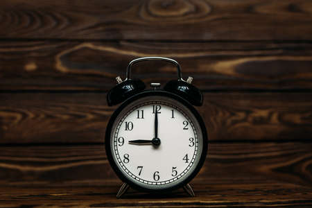 Clock on a wooden background. The clock shows the time of nine o'clock in the afternoon. The clock shows the time of nine o'clock in the morning. An image of a retro clock showing 09:00 pm / am. Copy spaceの写真素材