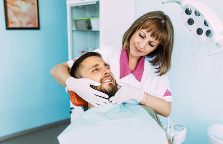A man treats his teeth at the dentist. Dental examination at the dentist. A snow-white smile. A young smiling man with beautiful teeth undergoing a dental examination. The doctor examines the patientの写真素材